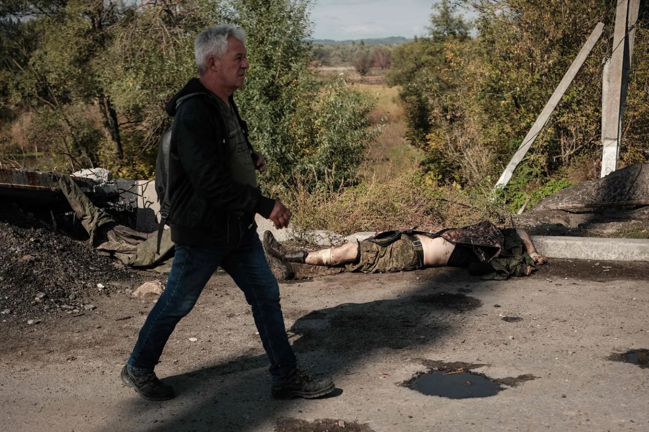 Kupyanskdan evakuatsiya qilinayotgan ukrainaliklardan biri rus askarining jasadi yonidan o‘tmoqda.
